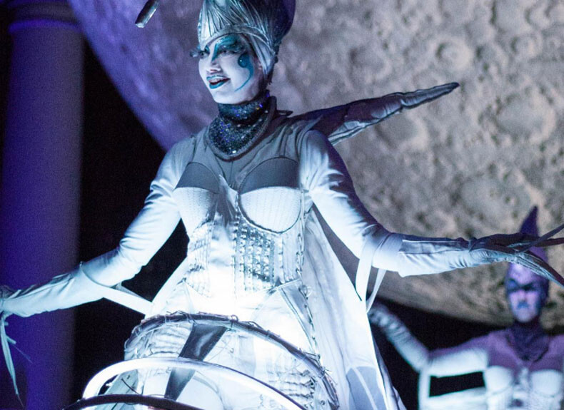 Person dressed in icy costume in front of giant sculpture of the moon