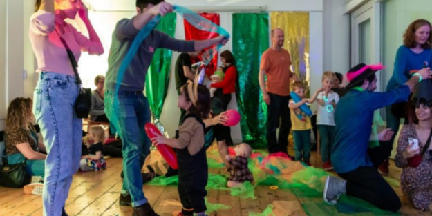 Families playing with long thin strips of coloured mesh and balloons